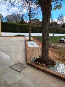Proyecto de paisajismo rústico en jardín con árboles y elementos decorativos de madera tratada.