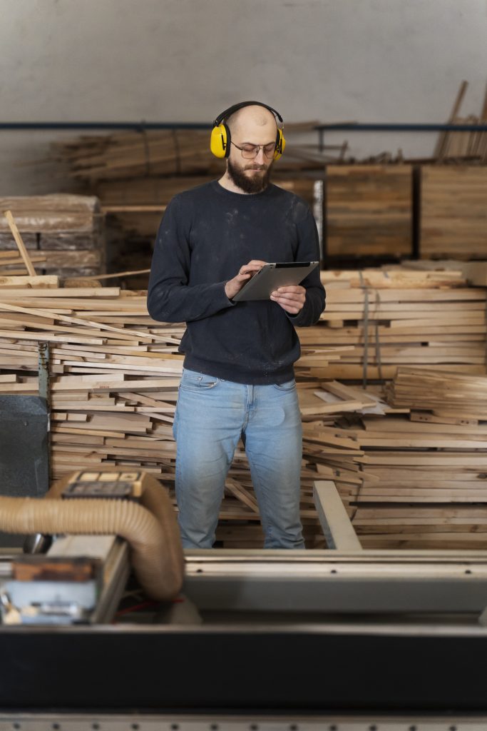 Personal de Traviesas de Tren gestionando el inventario de vigas de madera y pedidos mediante tablet en el almacén.