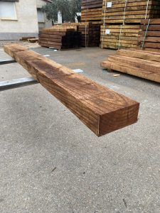 Primer plano de una traviesa de madera tratada en tono marrón oscuro para proyectos de construcción y decoración de exteriores.